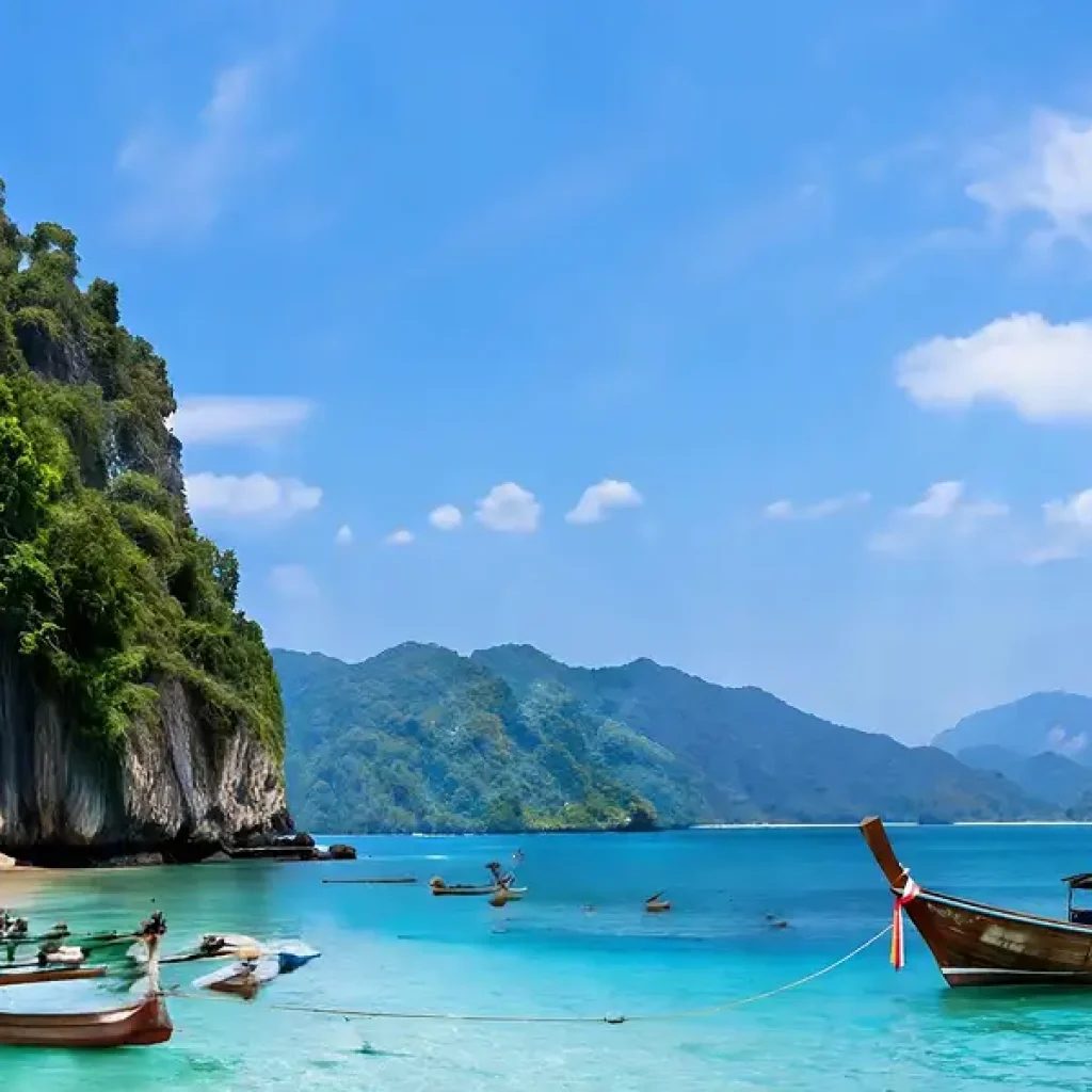 Longtail boats anchored in limestone cove Koh Lanta during island hopping tour