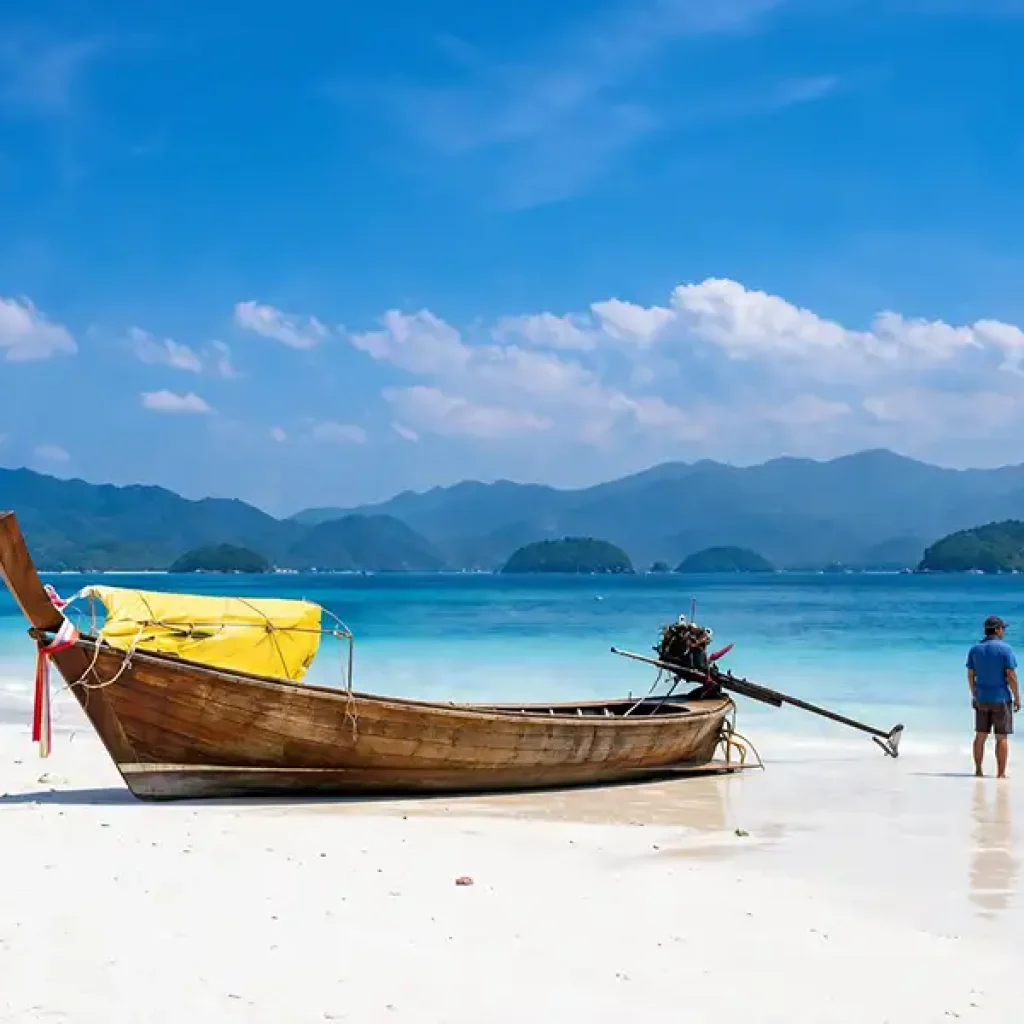 Longtail boat on white sand beach Koh Lanta with person enjoying sea view