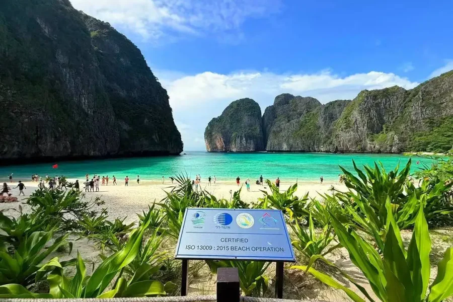 Maya Bay Phi Phi Island turquoise beach with limestone cliffs and ISO 13009 certified beach sign tourists
